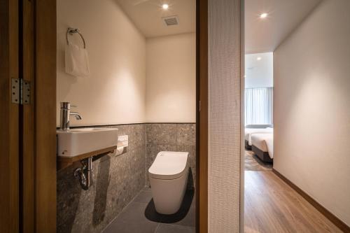 a bathroom with a toilet and a sink and a bed at Sotetsu Grand Fresa Bangkok in Bangkok