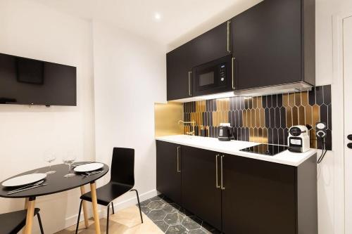 une cuisine avec des armoires noires et une table avec des chaises dans l'établissement Stockholm Studio - City center - Fontainebleau, à Fontainebleau