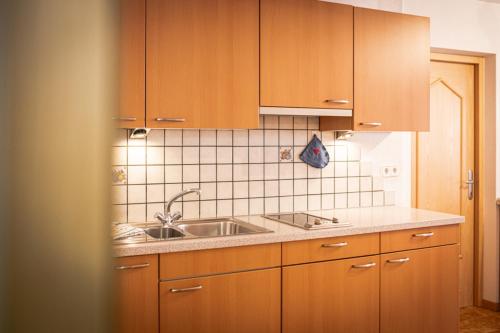 a kitchen with wooden cabinets and a sink at Weißnbachlhof in San Giovanni in Val Aurina