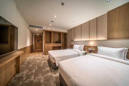 a hotel room with two beds and a television at Sotetsu Grand Fresa Bangkok in Bangkok