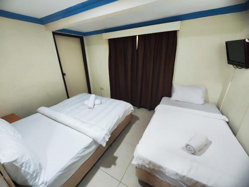 two twin beds in a room with a tv at Wings Grand Orchard Hotel in Kuala Lumpur