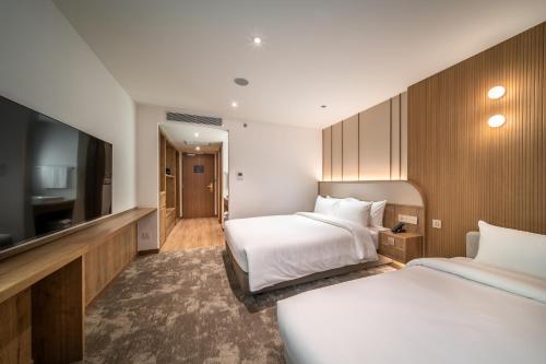 a hotel room with two beds and a flat screen tv at Sotetsu Grand Fresa Bangkok in Bangkok