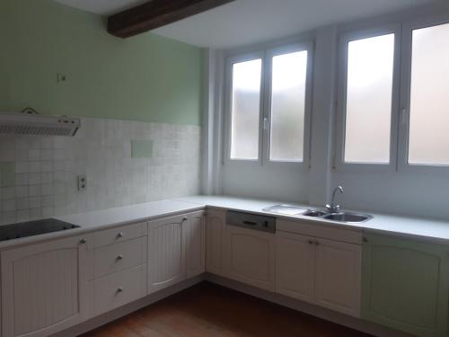 a kitchen with white cabinets and a sink and windows at Chambres d'Hôte Alarome in Huy