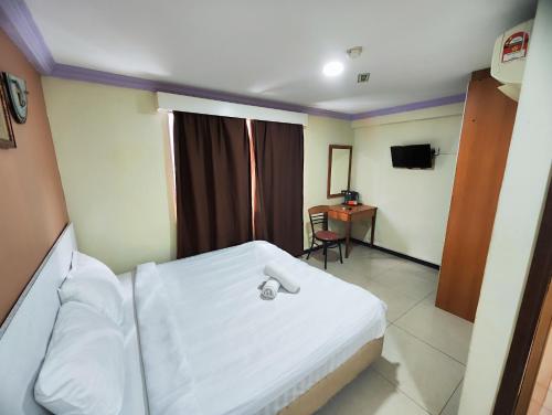 Schlafzimmer mit einem weißen Bett und einem Schreibtisch in der Unterkunft Wings Grand Orchard Hotel in Kuala Lumpur