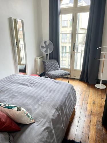 une chambre avec un lit, une chaise et des fenêtres dans l'établissement Bon'Appart centre-ville charme, à Fontainebleau
