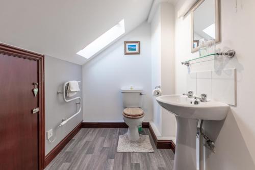 Baño blanco con lavabo y aseo en The Bothy, Landrake en Saltash