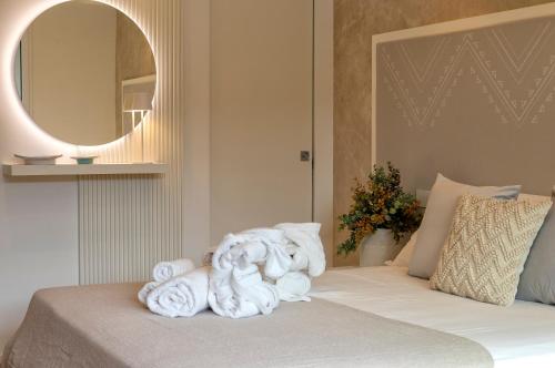 a bed with towels on it with a mirror at The Fetch - Residenze Esclusive sull'Acqua in Alghero