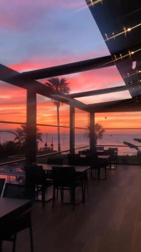 a patio with tables and chairs and a sunset at MAIA Luxury Beach Hotel & Spa in Guzelcamlı