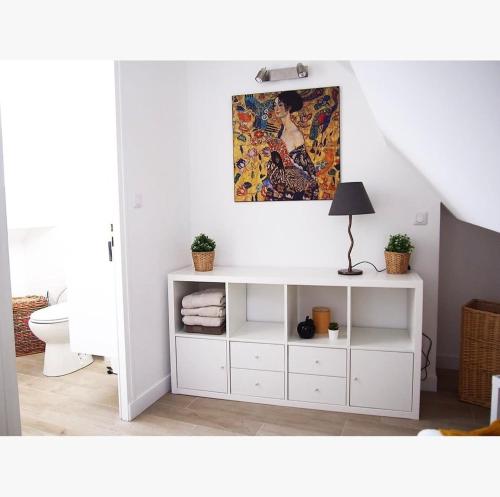 une armoire blanche dans une salle de bains avec un tableau mural dans l'établissement COCON NAPOLEON  Calme, à Fontainebleau