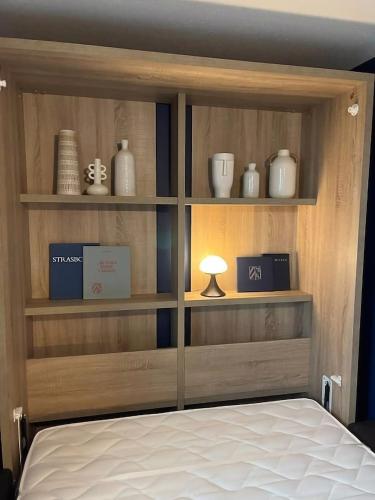 - une chambre avec une étagère en bois avec des vases et un lit dans l'établissement Le Tribunal - Studio près de l’avenue des Vosges, à Strasbourg