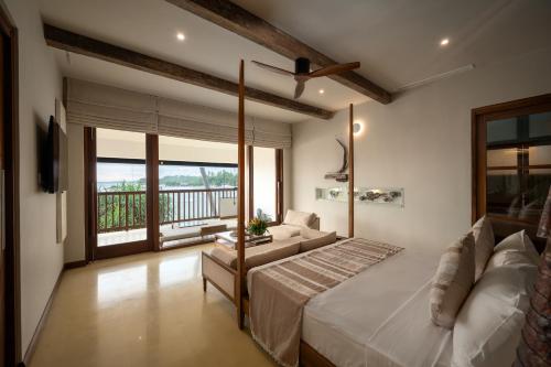 a bedroom with a bed and a couch and a balcony at Dickwella Resort and Spa in Dickwella