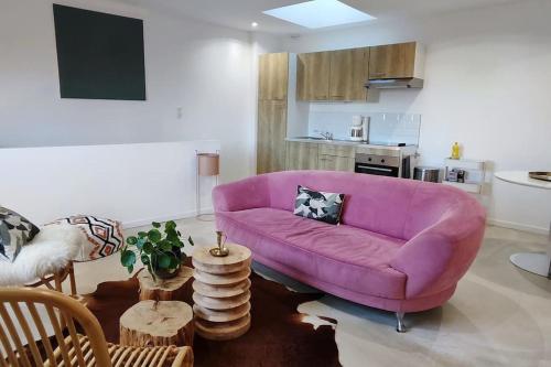 uma sala de estar com um sofá roxo e uma cozinha em L'élégante, 2 pers, centre ville Soyaux em Soyaux