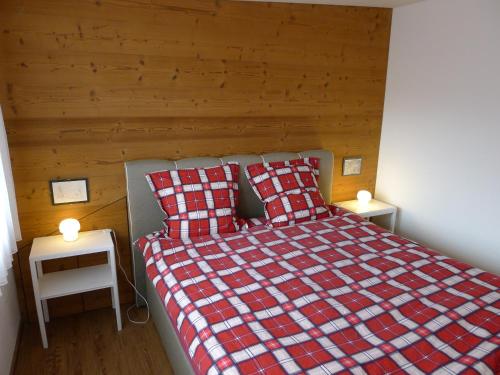 sypialnia z łóżkiem z czerwonym i białym kocem szachowym w obiekcie Elfe-Apartments Studio for 2 adults, balcony with lake and mountain view w mieście Emmetten