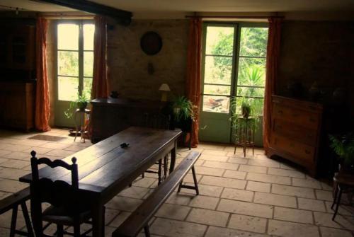 a living room with a wooden table and windows at Le tonnelier in Limogne-en-Quercy