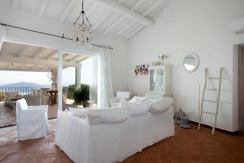 a bedroom with a bed with white sheets and chairs at Villa Florin in Porto Cervo