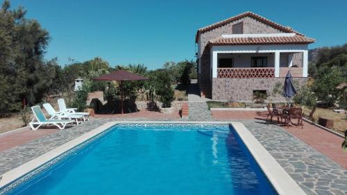 a villa with a swimming pool in front of a house at Casa Rural Las Adelfas in El Gastor