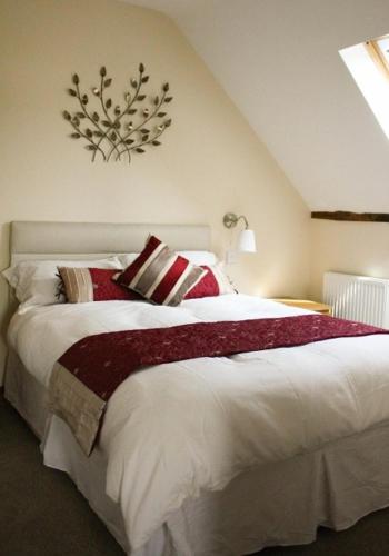 a bedroom with a large white bed with red pillows at The Hayloft at Carpenters Farm in Colchester