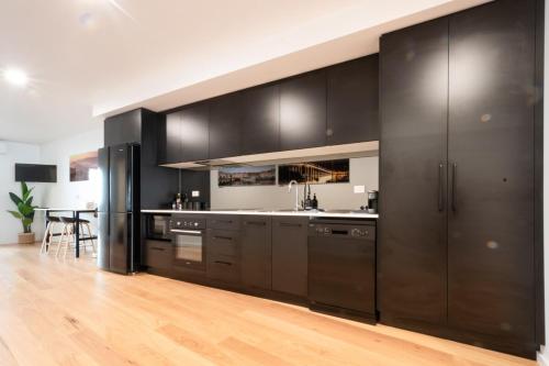 a kitchen with black cabinets and a wooden floor at Central & Modern Inner City Apartment with Wi-Fi in Launceston