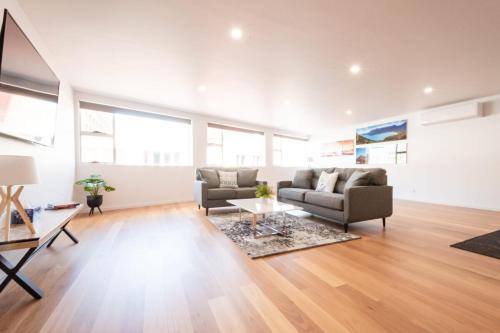 a living room with two couches and a table at Central & Modern Inner City Apartment with Wi-Fi in Launceston