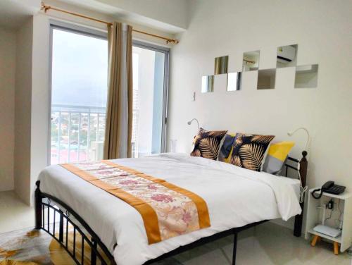 a bedroom with a bed with a large window at Goldentel at Inspiria Condo Davao City in Davao City