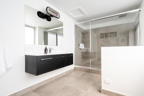 y baño con ducha, lavabo y espejo. en Central & Modern Inner City Apartment with Wi-Fi, en Launceston