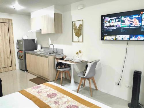a kitchen with a table and chairs and a tv on the wall at Goldentel at Inspiria Condo Davao City in Davao City