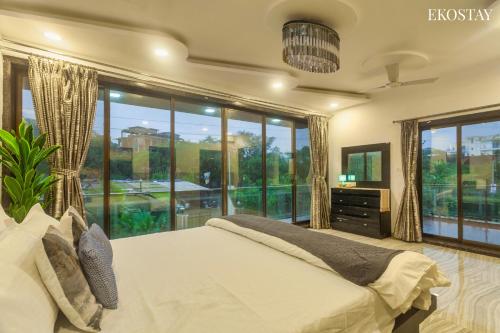 ein Schlafzimmer mit einem Bett und einem großen Fenster in der Unterkunft EKOSTAY Gold - Iris Villa in Lonavla