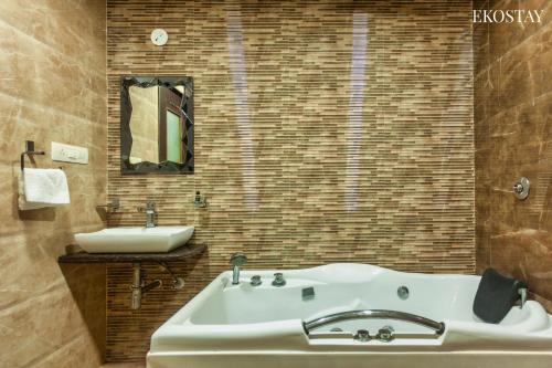 ein Badezimmer mit einer weißen Badewanne und einem Waschbecken in der Unterkunft EKOSTAY Gold - Iris Villa in Lonavla