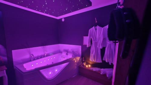 een paarse badkamer met een bad en een wastafel bij La Vallée Douce 