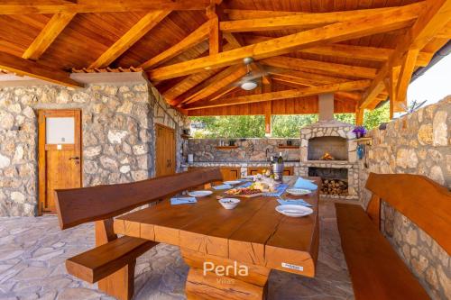 a dining room with a table and a stone fireplace at House CAPRI with heated pool and sea view in Klimno