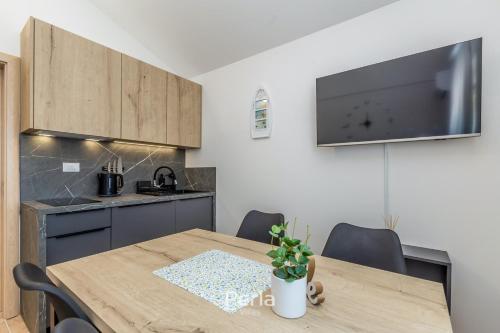 a kitchen with a wooden table and a tv on the wall at House CAPRI with heated pool and sea view in Klimno