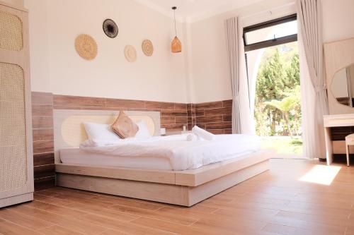 a bedroom with a large white bed and a window at White Villa Đà Lạt in Da Lat