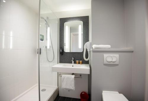 a white bathroom with a sink and a shower at Ibis Saint-Genis-Pouilly Genève in Saint-Genis-Pouilly