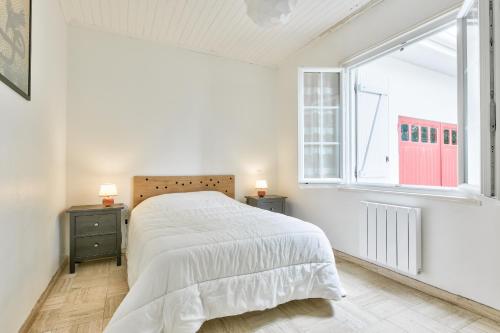 une chambre blanche avec un grand lit et une fenêtre dans l'établissement Maison pour 10 - jardin - 600 m de la plage, à Andernos-les-Bains
