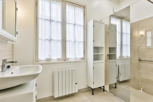une salle de bain blanche avec un lavabo et un miroir dans l'établissement Maison pour 10 - jardin - 600 m de la plage, à Andernos-les-Bains