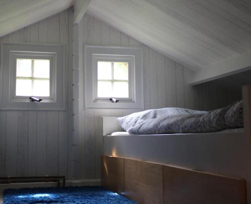 a bedroom with two windows and a bed in it at Blockhouse Nicks Lodge in Hatten