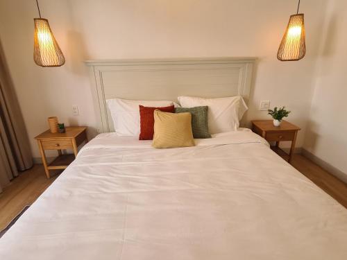 a large white bed in a room with two tables at TerraCotta Beachfront Villa Phan Thiet in Phan Thiet