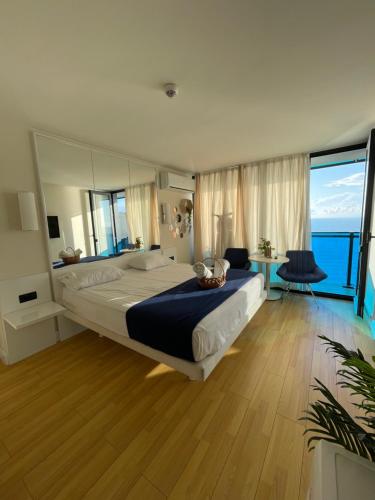 a bedroom with a large bed and a large window at PANORAMA Black Sea Side ApartHotel in Batumi
