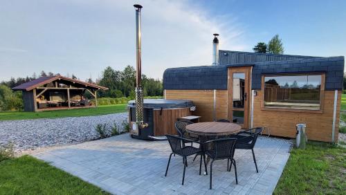 een kleine hut met een tafel en stoelen en een barbecue bij Sila terases in Madona