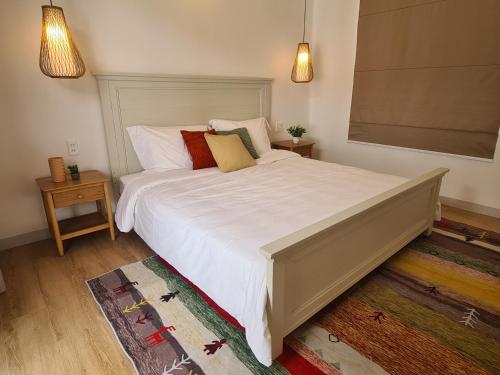 a bedroom with a large white bed with pillows at TerraCotta Beachfront Villa Phan Thiet in Phan Thiet