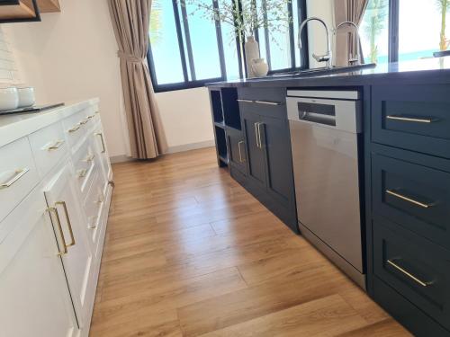 a kitchen with blue cabinets and a wooden floor at TerraCotta Beachfront Villa Phan Thiet in Phan Thiet
