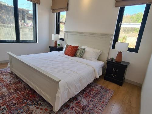 a bedroom with a large white bed with two windows at TerraCotta Beachfront Villa Phan Thiet in Phan Thiet