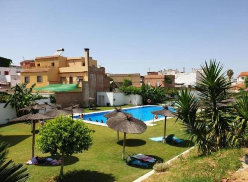 una piscina con sombrillas y gente en la hierba en Apartamento en Sevilla con piscina y parking, en La Algaba