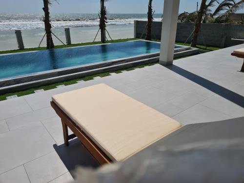 a bench in front of a swimming pool at TerraCotta Beachfront Villa Phan Thiet in Phan Thiet