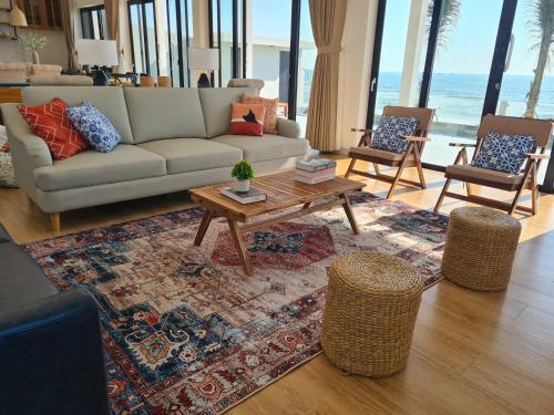 a living room with a couch and a table and chairs at TerraCotta Beachfront Villa Phan Thiet in Phan Thiet