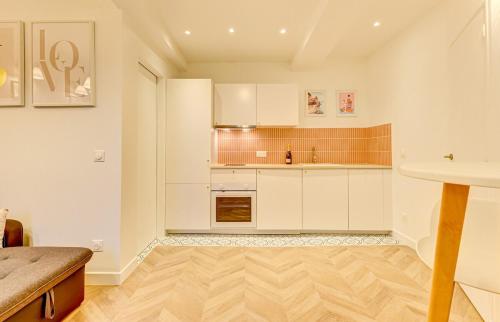 a kitchen with white cabinets and a wooden floor at Boudoir - Spa & Chateau Fontainebleau in Avon