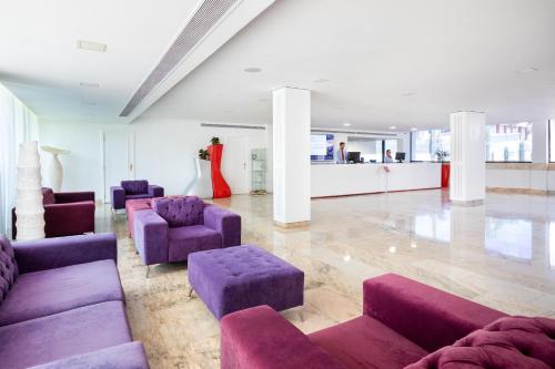 a large room with purple chairs and couches at Alexandre La Siesta in Playa de las Americas
