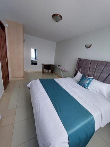 1 dormitorio con 1 cama grande y edredón azul y blanco en Roma Stays - Budget Studio in Busia (Opp Shell petrol Station) en Busia