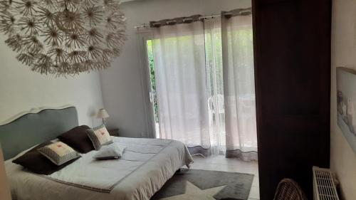 a bedroom with a bed and a large window at Le Temps Des Cerises. in Vinsobres