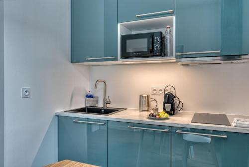 La cuisine est équipée de placards bleus, d'un évier et d'un four micro-ondes. dans l'établissement Sainte-Catherine by Yumē, à Toulouse